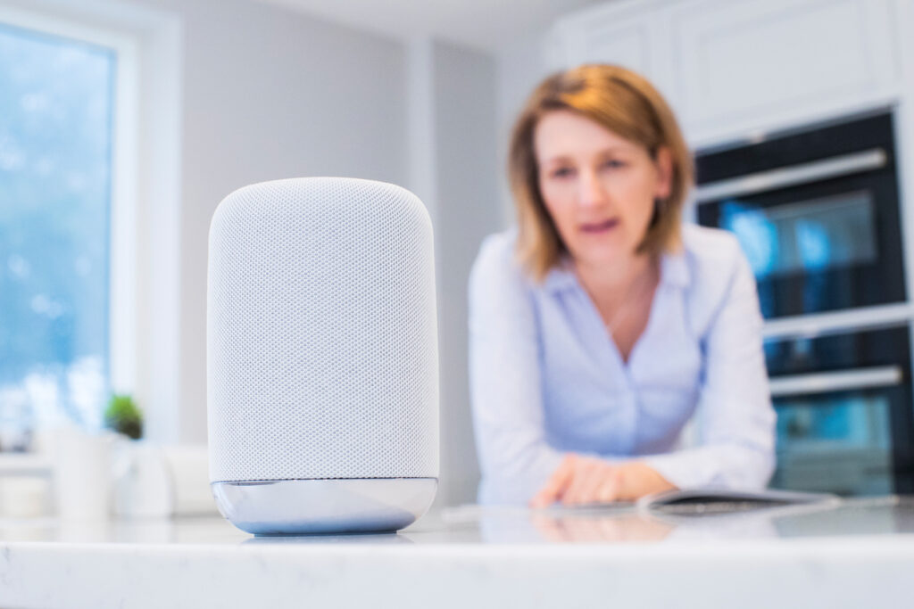 Woman In Kitchen Asking Digital Assistant Question. A.I. concept