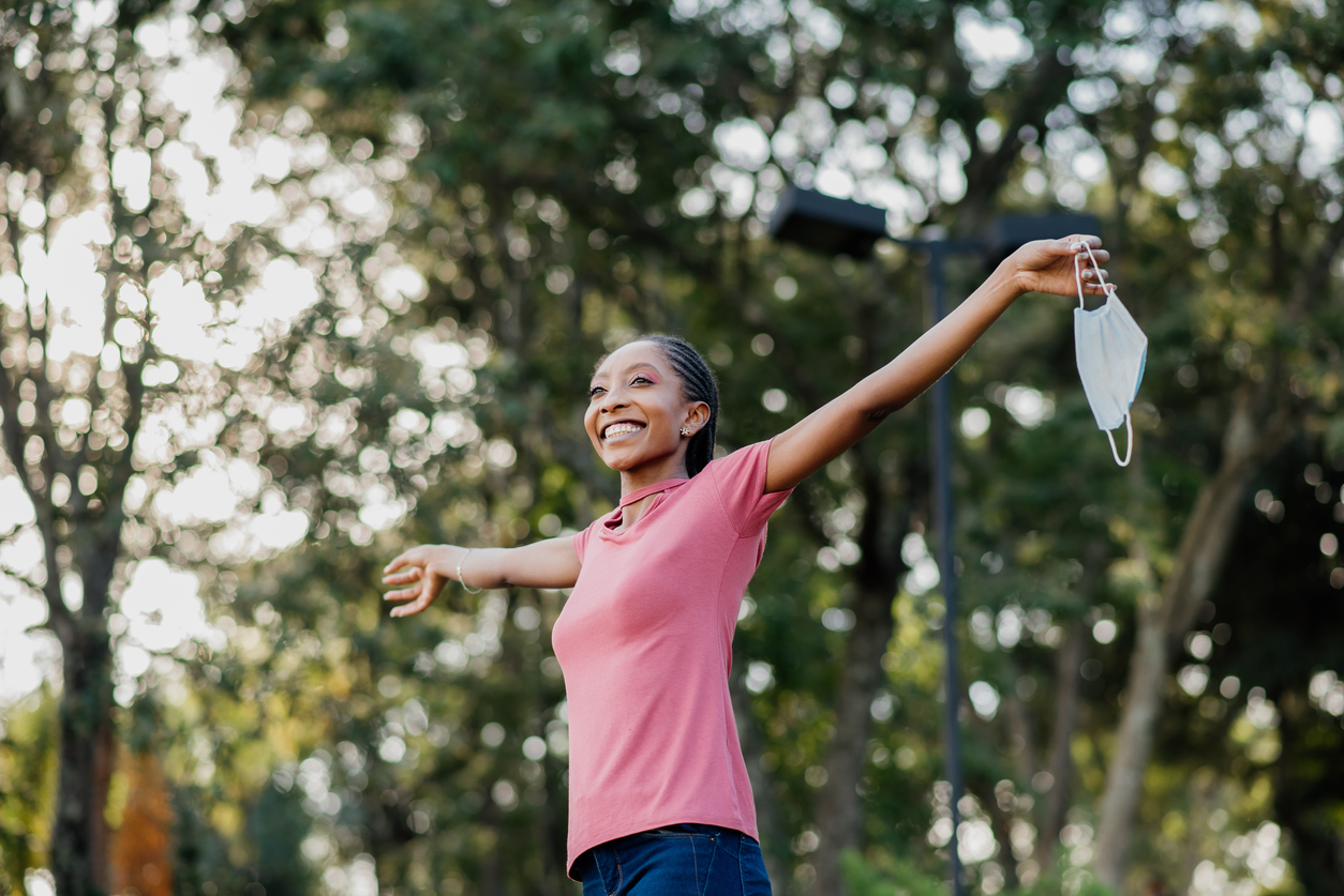 Young woman enjoying the outdoor air while holding her mask in one hand